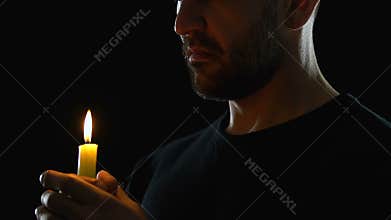 Young man looking to heaven and blowing candle, blessing God, dark background