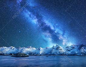 Bright Milky Way over snow covered mountains and sea at night