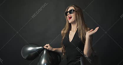 Smiling woman with black balloons and shopping bag