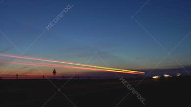 Timelapse traffic on a country road at night on the Sunset. Cars with headlights on go on the highway track in summer