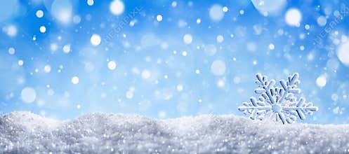 Winter snow background with decorative snowflake against blue sky. Banner format. Beautiful wintertime holiday scene