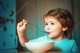 Kid eating. Little boy having breakfast in the kitchen. Parenthood. Happy child. Young kid sitting on the table eating