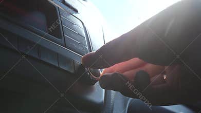 Man turns on the music in the car. Radio in the sun. Man`s hand on the car key