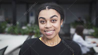 Happy young black woman looking to the camera and smiling in the office