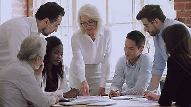 Diverse business team and old woman leader brainstorm on paperwork