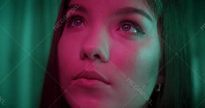 Close-up eyes Portrait of caucasian beautiful confident girl neon light look into camera green background evening