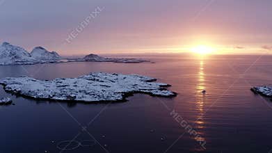 Drone sideway move video of fishing boat sailing on fishing during sunrise in arctic lofoten islands. sunlight and snow mountains.