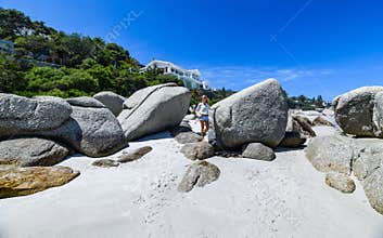 A young woman leaning on the boulders of clifton beach in the capetown area of south africa.