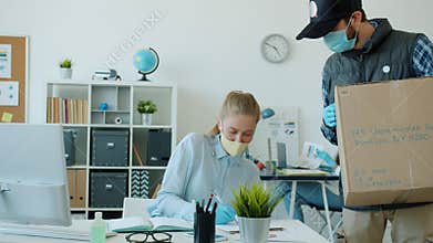 Woman in face mask and gloves getting parcel delivery in office during covid 19 pandemic