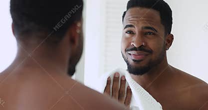 Happy young shirtless afro ethnicity man wiping face with towel.