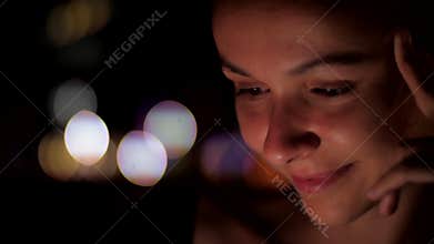 Young european woman sits outside at night and looks down