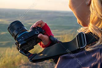 Young woman photographer shows her Sony A6500 Mirrorless SLR camera, using the Auto setting.