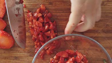 Woman hands cutting strawberries on wooden cutting board