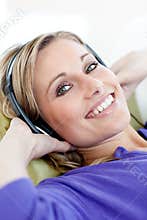 Charming woman lying down on sofa listening music