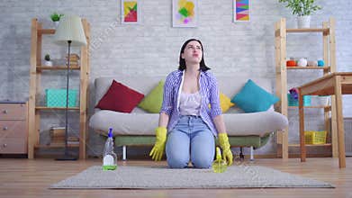 Young woman in gloves with discontent cleans the carpet with her hands