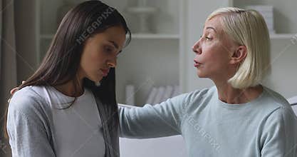 Caring mature mother comforting consoling sad depressed young daughter