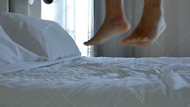 Closeup bare feet man jumping on bedroom footage.