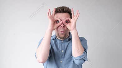 Man holding fingers near eyes like glasses. Mask like super hero or owl.