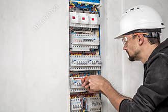 Man, an electrical technician working in a switchboard with fuses. Installation and connection of electrical equipment