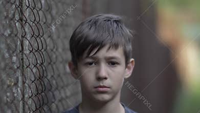 Refugee sad boy looks compassionately at the camera, pain on face, moving camera, close up