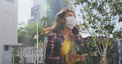 Mixed race woman wearing medical coronavirus mask on the street