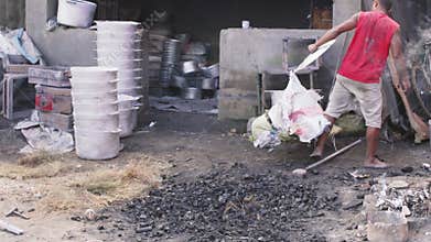 Ambatolampy, Madagascar - April 25, 2019: Panning shot over aluminium processing factory, metal cans are melting down in pots with