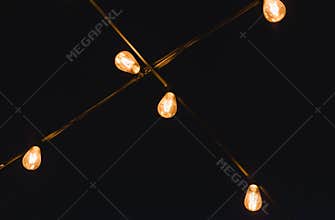 Light bulb decor in outdoor party. Decorative outdoor string lights at night time. Golden glowing garlandon in wedding