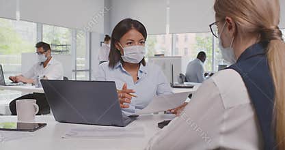 View over shoulder of caucasian businesswoman collaborate with african colleague in protective mask
