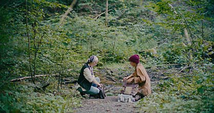 Friends Packing Bags While Crouching In Forest