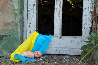 A children's doll lies on the flags of Ukraine in a blown-up house from missiles, the war in Ukraine, the death of