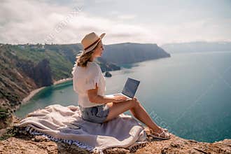 Freelance women sea working on the computer. Good looking middle aged woman typing on a laptop keyboard outdoors with a