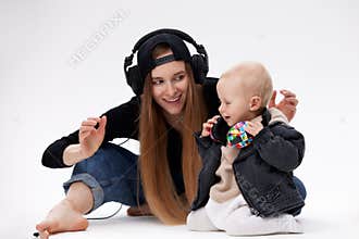 A young cute barefoot mom in a black top, blue jeans and a black baseball cap and her toddler in a black motorcycle
