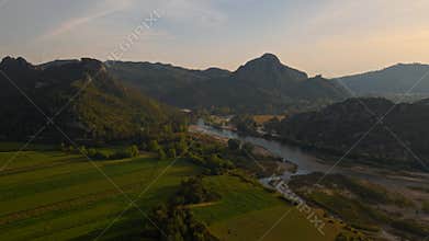 aerial scenic landscape with green fields, meadows, curved mountain river and mountain ridge with high mountains and