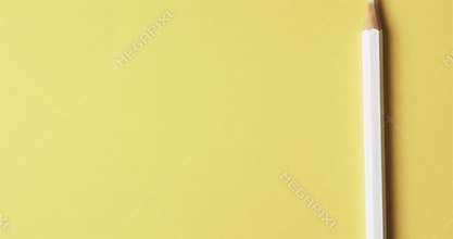 Overhead view of white crayon with copy space on yellow background, in slow motion