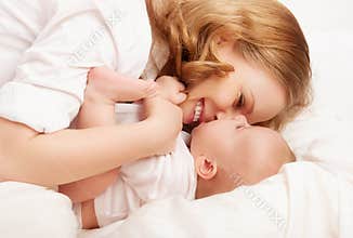Happy family. baby and mother play, kiss, tickle, laugh in bed