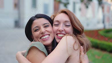 Best friends embracing while smiling in the street