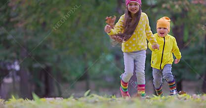 Happy kids, laughing girl and boy playing outdoor with colorful fallen leaves in autumn nature. Running children in a park, 4k vid