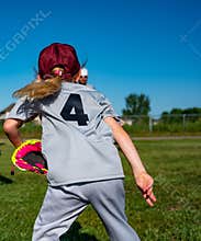 Blonde Caucasian girl with a hat throwing a baseball