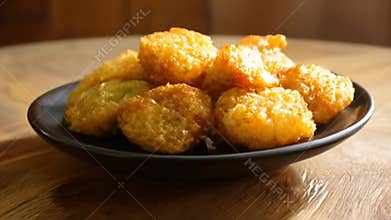 Pile of Golden Bu?uelos on a Black Plate Displayed on Wooden Table Ready to Eat Sweet and Crispy Dessert