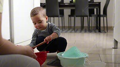 Mother and baby playing with pots and pans in the kitchen, goofing around and having fun
