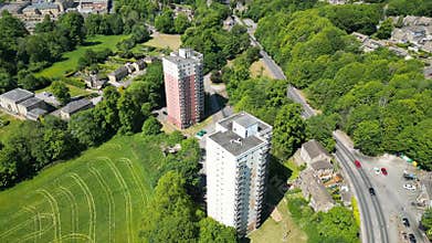 Scenic drone footage of Berry Brow High Rise Flats, between green plants in West Yorkshire