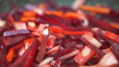 A close up of a pile of red and orange vegetables, including carrots and beets. The vegetables are cut into small pieces and