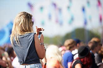 Young Woman At Outdoor Music Festival Using Mobile Phone