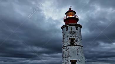 Dramatic lighthouse beacon illuminating stormy skies with dynamic cloud movement