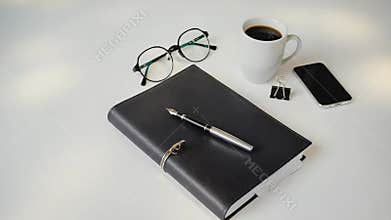 Business desk showing agenda, pen, glasses and coffee cup with smartphone