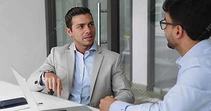Two men professionals engaged in focused conversation in modern office