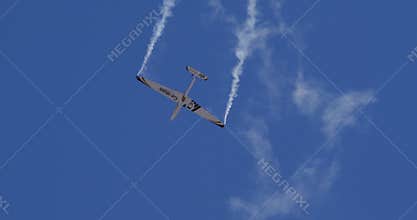 Glider Performing Aerobatics with White Smoke Trails in Clear Blue Sky