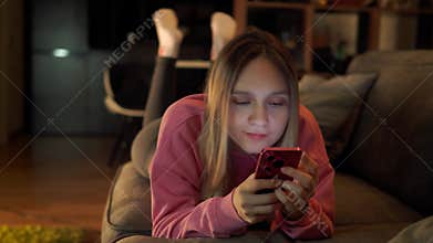 A woman listening to music from her smartphone. woman, who has earbuds in her ears, is intently looking at the screen of