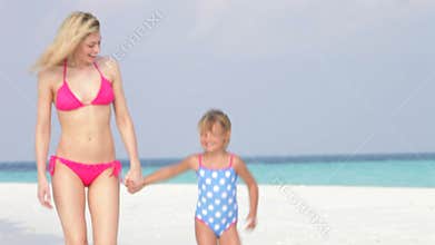 Mother And Daughter Walking Along Beautiful Beach