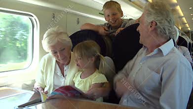 Grandparents And Grandchildren Relaxing On Train Journey